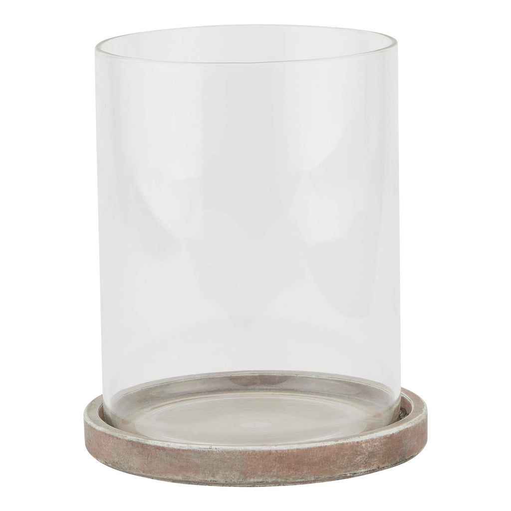 Front view of a decorative lantern with a tall clear cylindrical sleeve seated in a shallow round base with brown, grey and pale weathered markings.