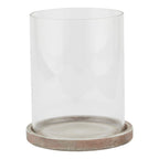 Front view of a decorative lantern with a tall clear cylindrical sleeve seated in a shallow round base with brown, grey and pale weathered markings.