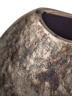 Close-up of the dipped rim and dark interior above a textured bronze-toned surface with green-grey markings.