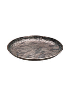 Angled view of a shallow round platter with a mottled bronze and green surface and gently raised rim.