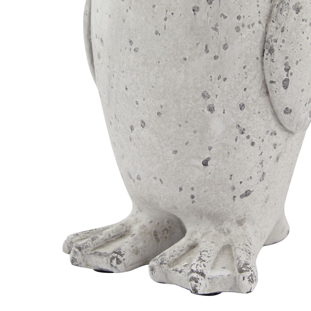 Close-up of the penguin ornament's lower body and wide webbed feet, showing raised toe details and grey flecks over the off-white finish.