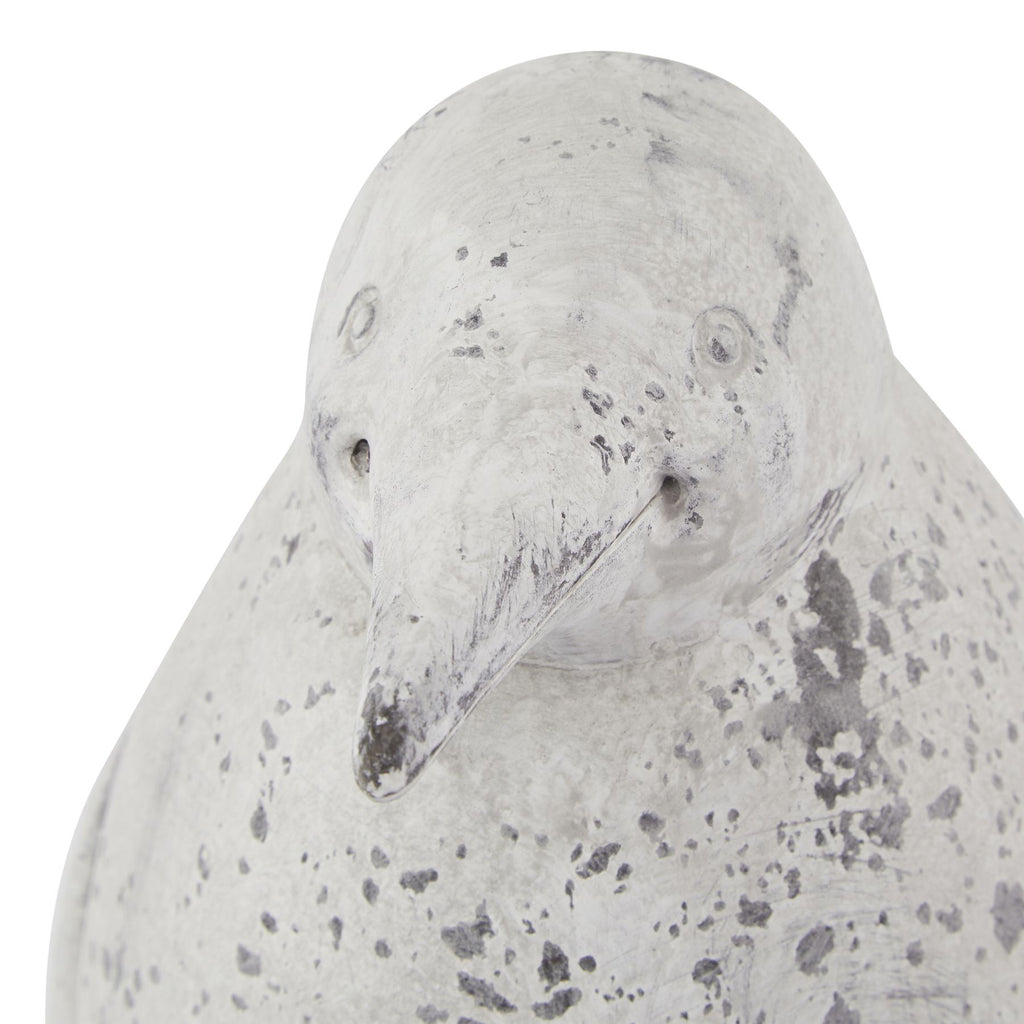 Close-up of the penguin ornament's head, with circular eyes, a tapered beak and dark grey mottling across the pale surface.