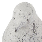 Close-up of the penguin ornament's head, with circular eyes, a tapered beak and dark grey mottling across the pale surface.