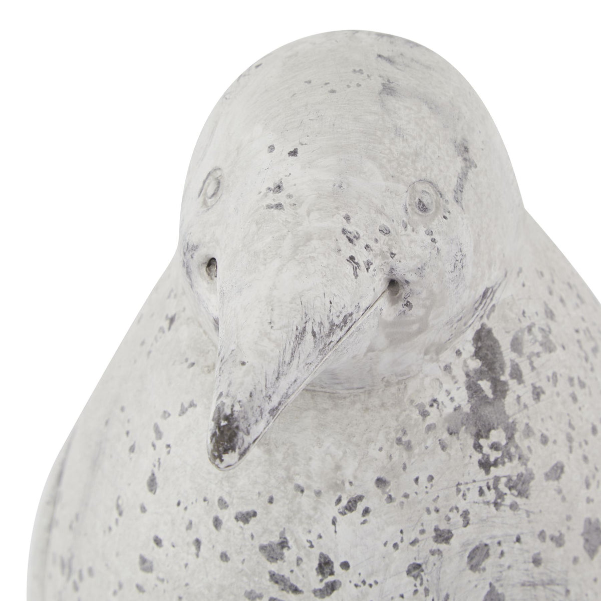Close-up of the penguin ornament's head, with circular eyes, a tapered beak and dark grey mottling across the pale surface.