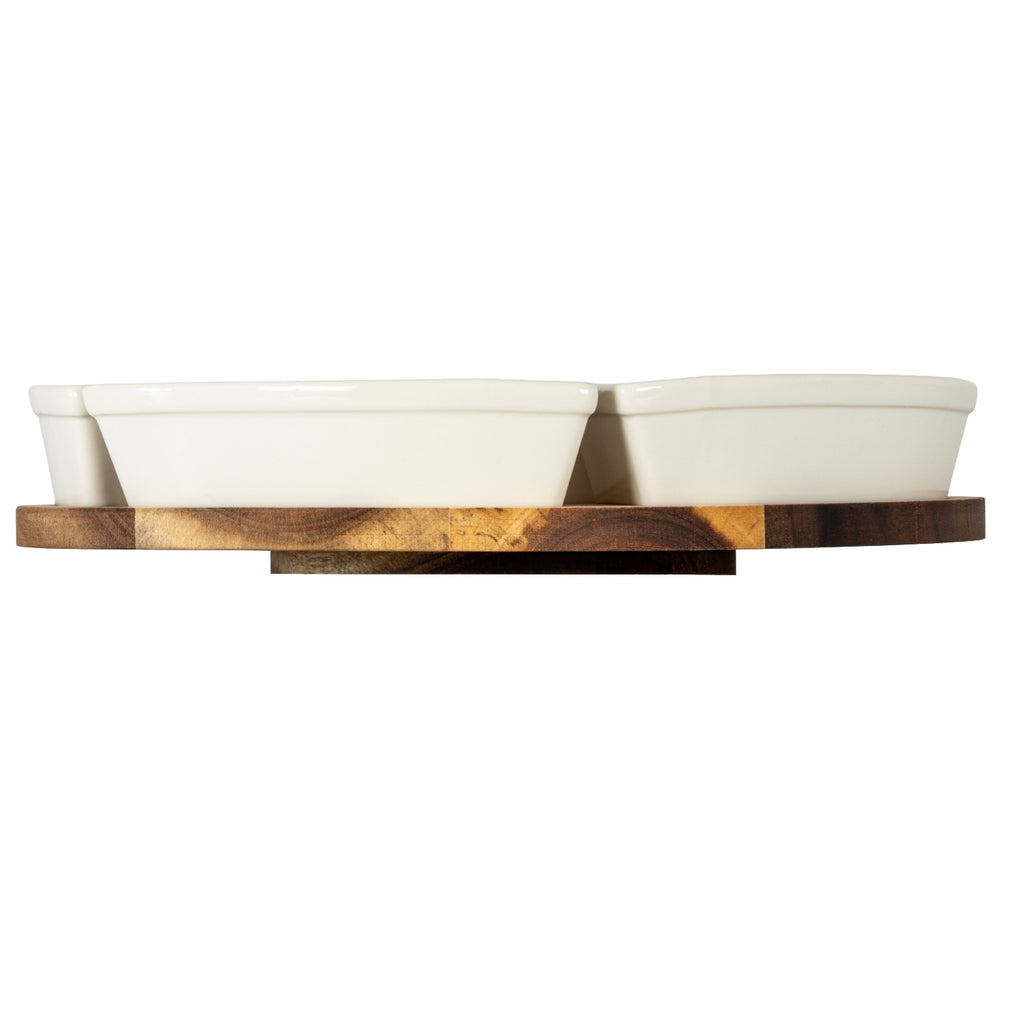 Low side view of warm-white dishes on the brown grained platform, with its smaller base plate visible beneath.