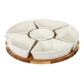 Angled view of five glossy warm-white wedge dishes surrounding a round bowl on a circular brown grained platform.