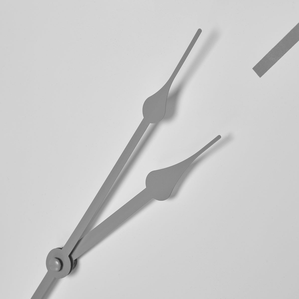 Close-up of the grey clock hands, showing their widened decorative shapes against the pale dial.