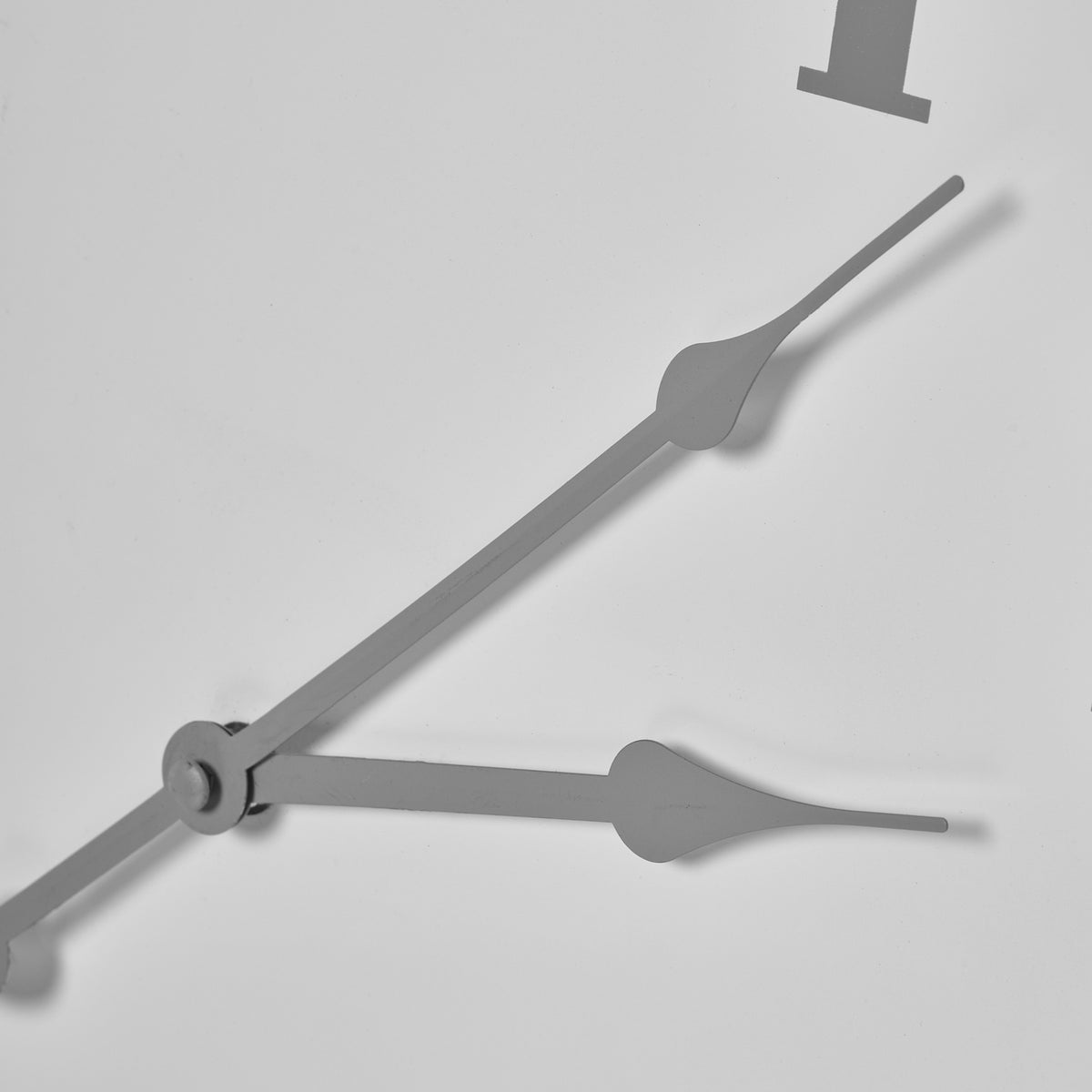 Close-up of the clock's grey hands, showing their curved decorative shapes against the pale face.