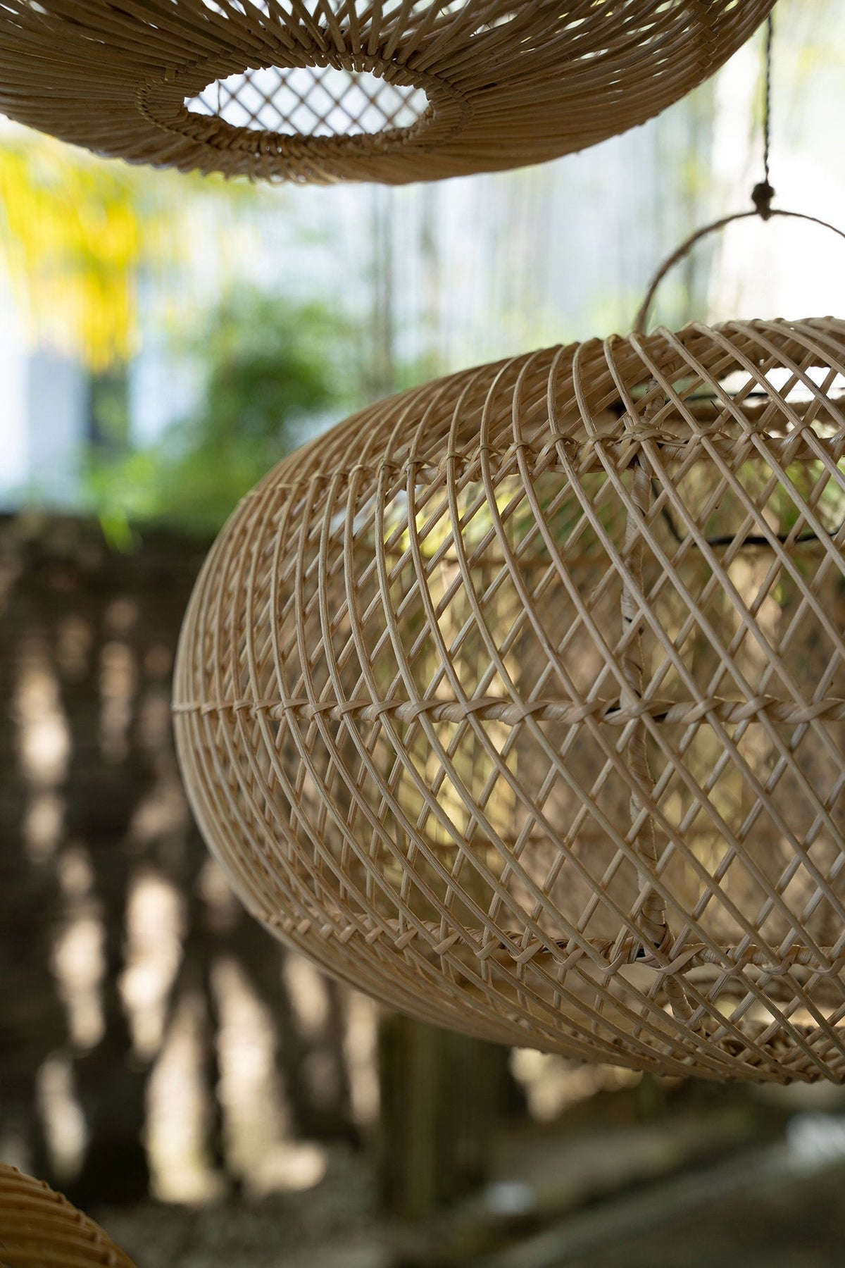 Wholly Rattan Pendant Light – Natural, Medium – close hanging view among greenery