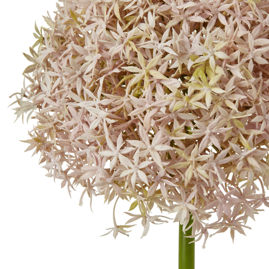 Close-up of the artificial flower head showing overlapping star-shaped florets in pale blush and lilac tones.