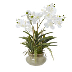 Artificial potted orchid arrangement with arching white blooms, green buds, broad leaves and trailing fern-like fronds above a rounded taupe-speckled pot.