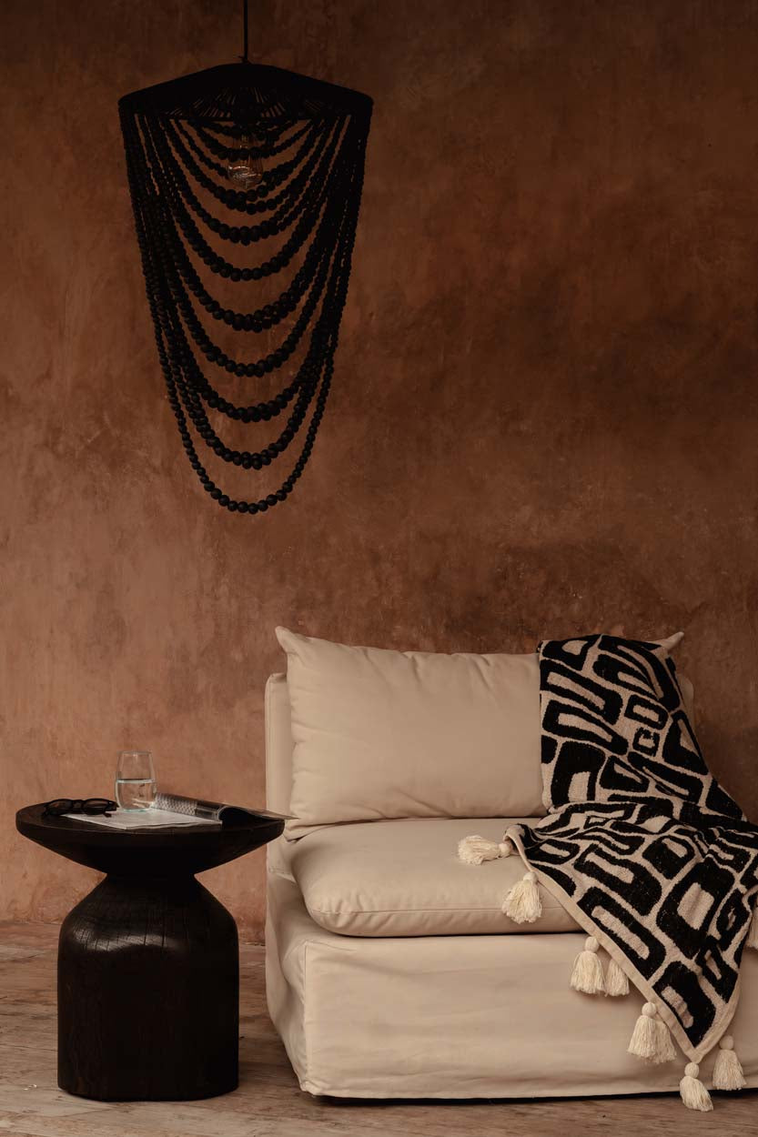 Wooden Bead Chandelier – Black, Large – styled above a lounge against a terracotta wall