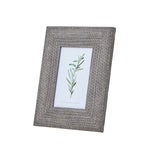 Angled front view of a grey-brown photo frame with a broad woven-texture border and a green botanical illustration in the opening.