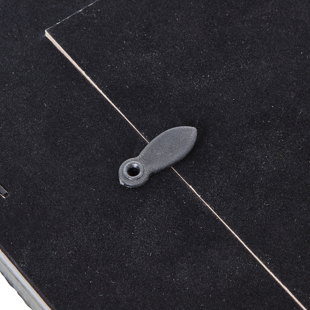 Detail of an oval turn tab crossing the edge of the dark rear panel.