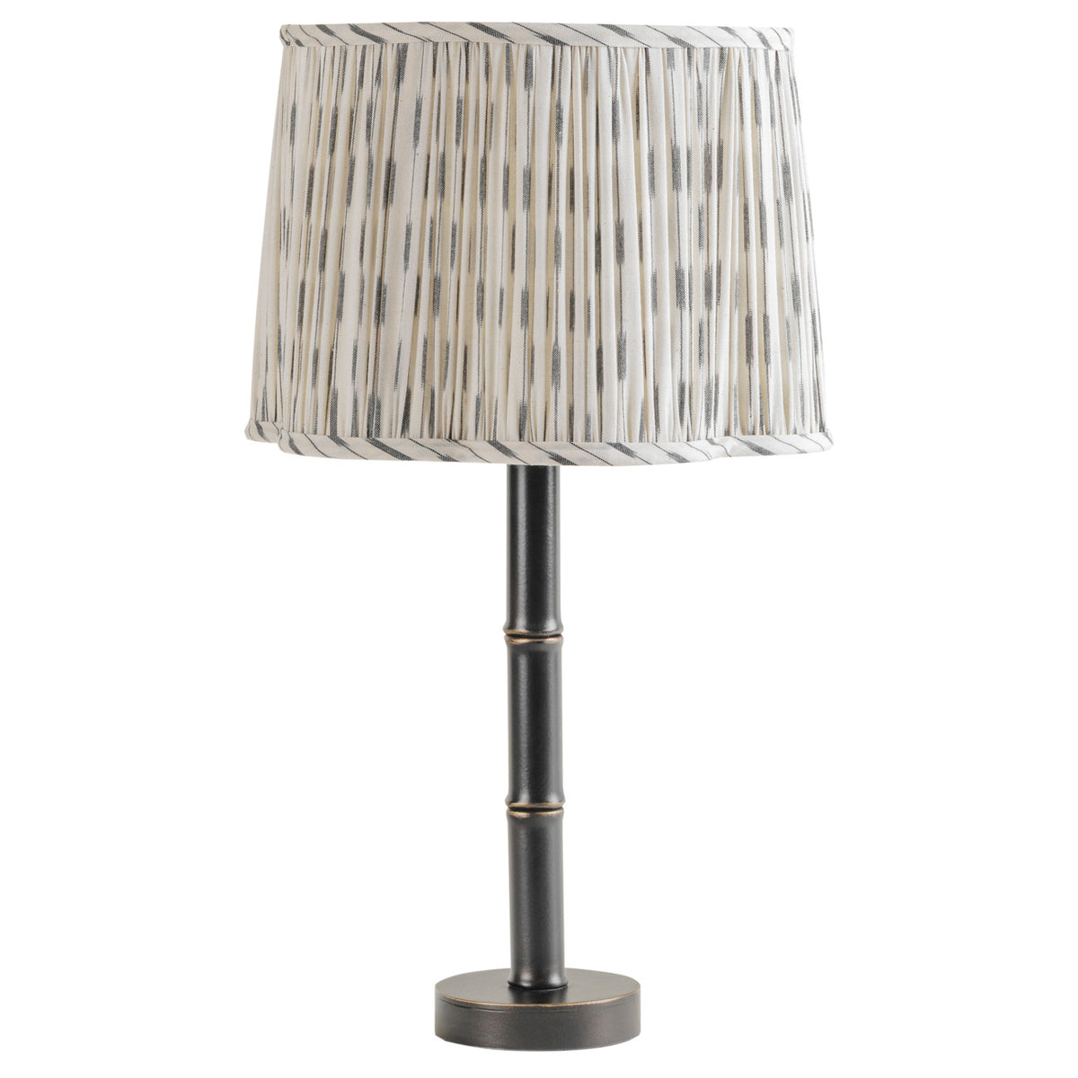 Unlit table lamp with a gathered cream and grey patterned shade, dark bamboo-like column and circular foot.