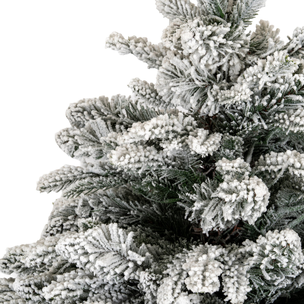 Close-up of dense green artificial fir branches coated with thick, granular white flocking.