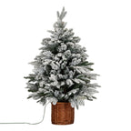 Artificial Christmas tree with an irregular tapered outline, heavily snow-flocked green branches and a tall brown woven pot, with a green lead extending to the left.