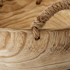 Close-up of a fibrous wrapped handle passing through a rim hole beside the bowl's golden-brown grain.