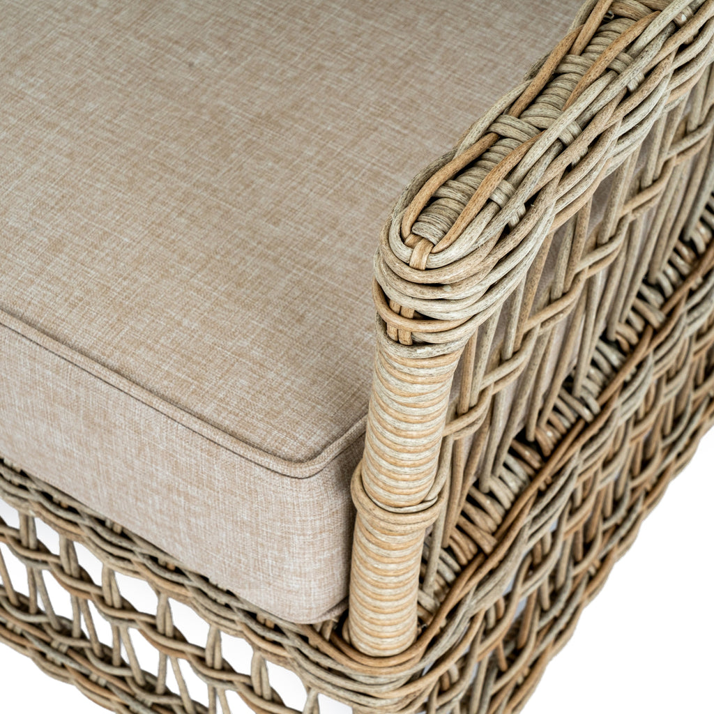 Close view of the rounded wrapped armrest and lattice side beside the piped edge of an oatmeal seat cushion.