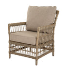 Matching lounge armchair viewed at an angle, showing oatmeal seat and back cushions within a pale open-lattice frame.
