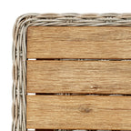Top corner of the coffee table showing brown slats with pale streaks and a curved woven border.